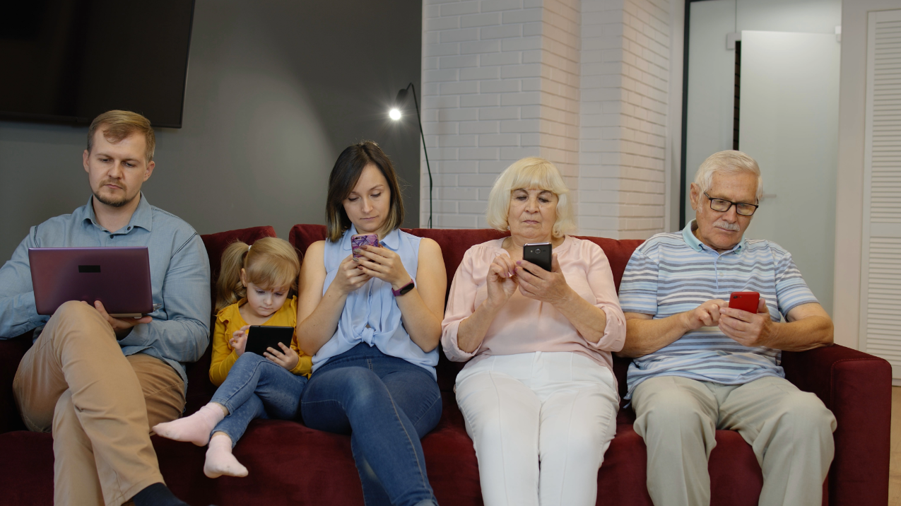 Picture of retired couple watching TV with their grand kids not having fun.