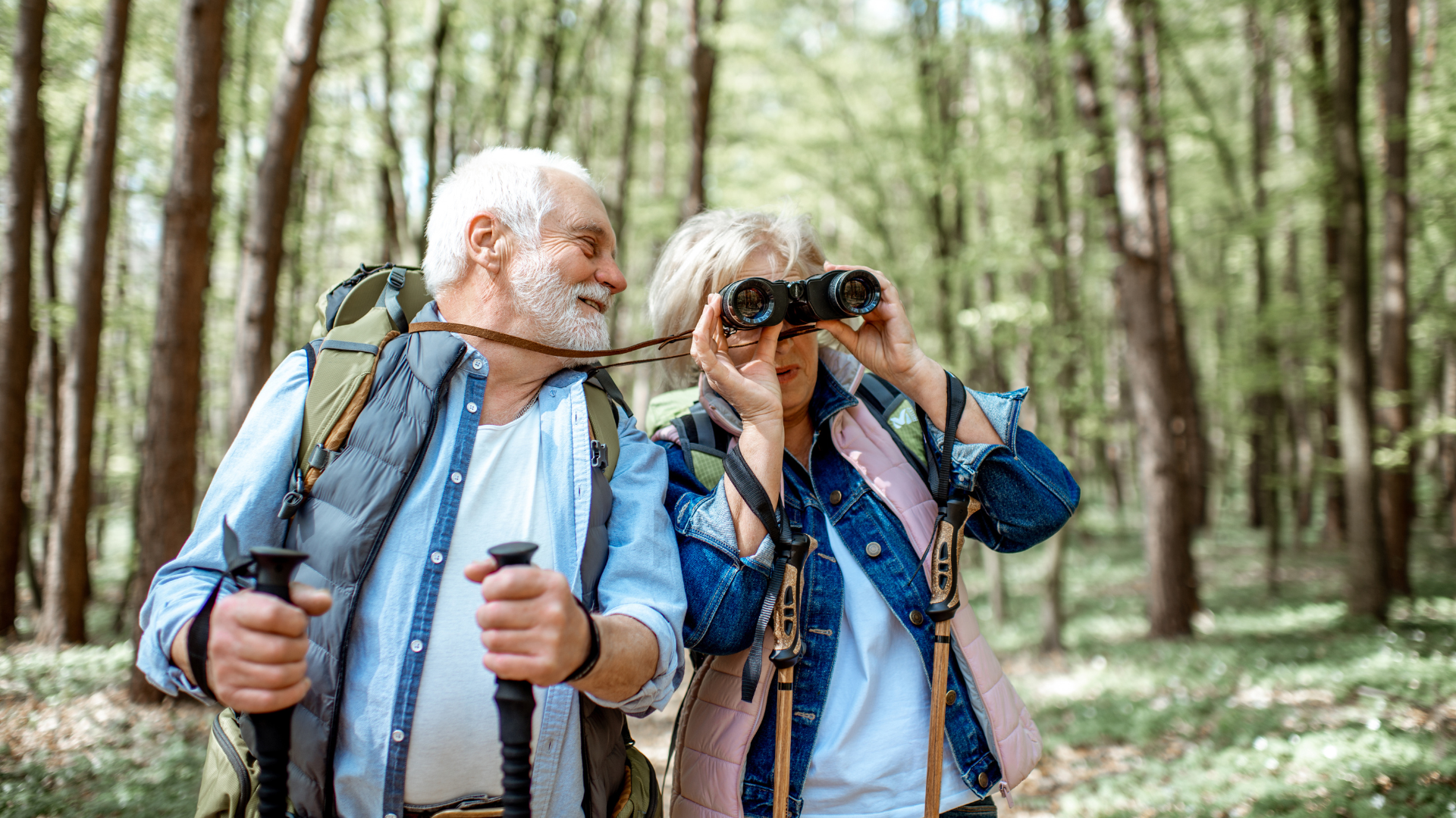 Image of couple hiking with wife looking through a telescope while husband is smiling looking at her